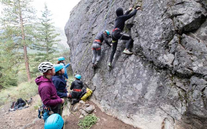 two students ascend over a rocky landscape with a mountain in the background